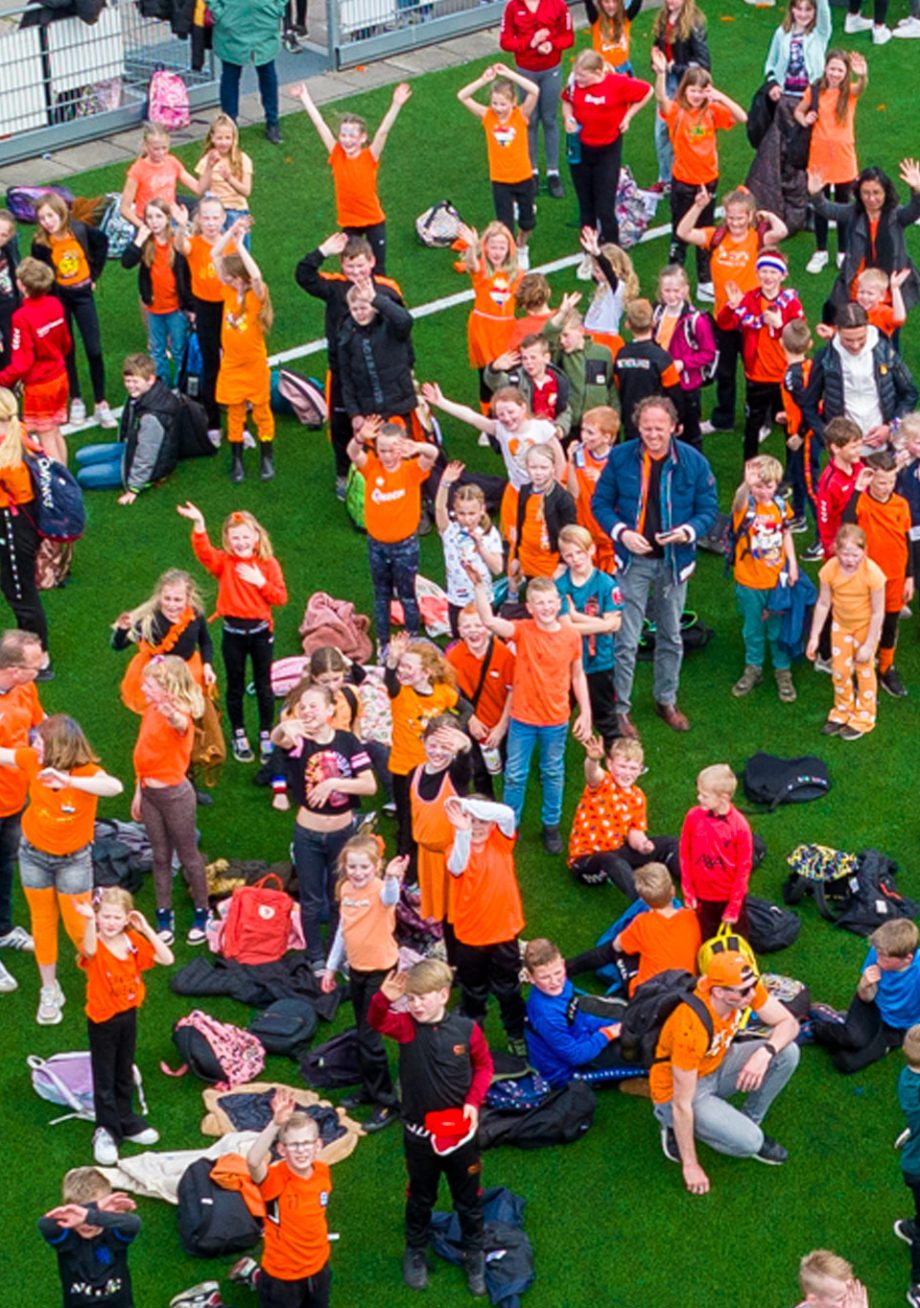 Inwoners gemeente Emmen tijdens Koningsspelen op een grasveld gekleed in het oranje
