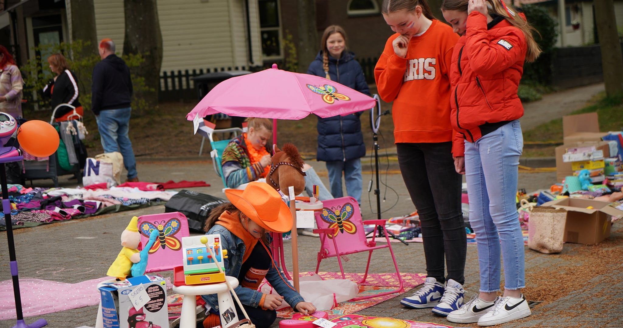 Jonge meiden staan bij een kleedjesmarkt gekleed in het oranje.