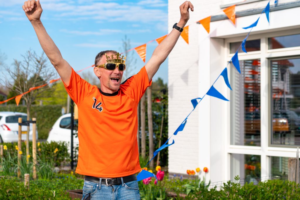Dutch man celebrating kings day on the road in street party dressed in orange in Holland.
