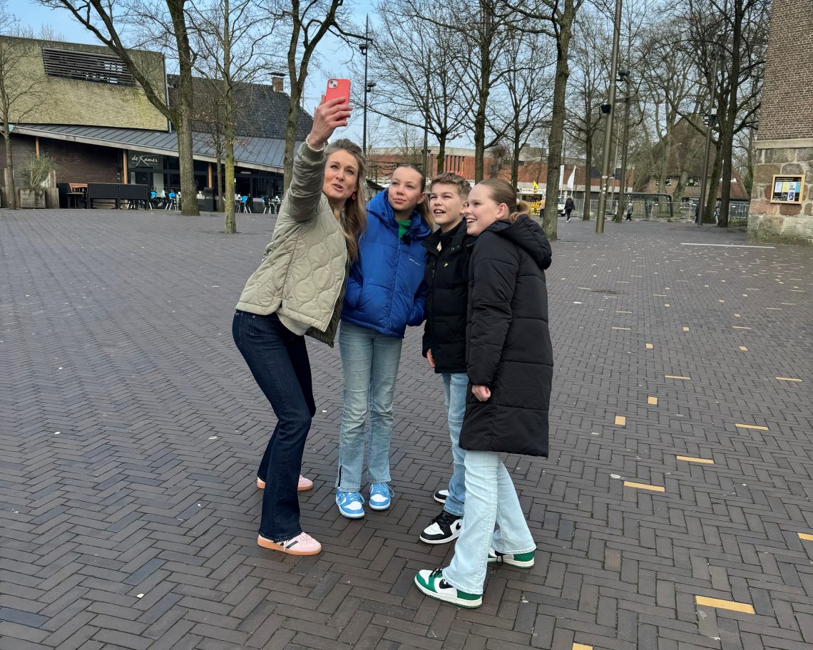 Presentatrice Margreet Beetsma voor de Grote Kerk maakt een selfie met drie jongeren.