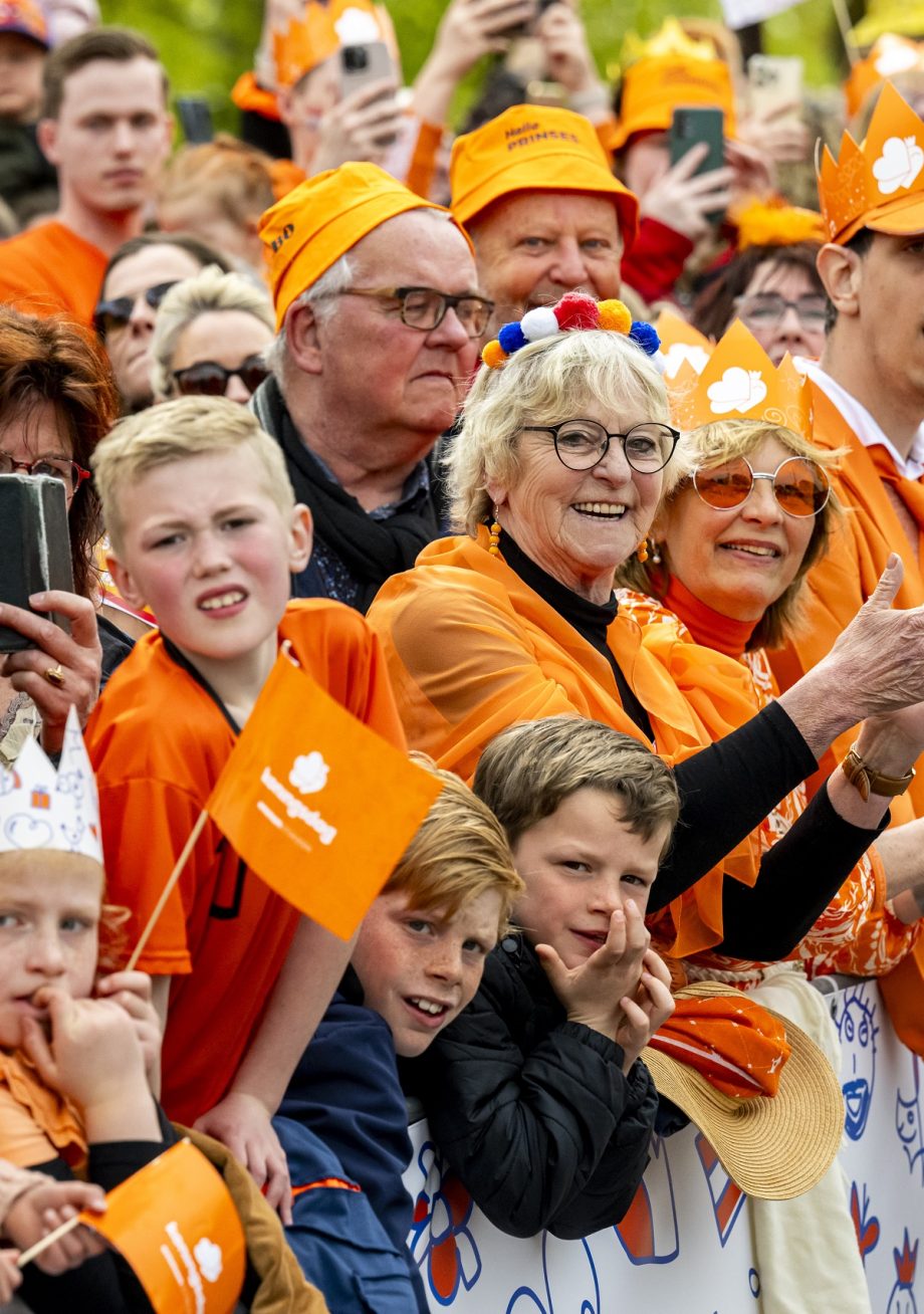 Publiek gekleed in het oranje langs de route tijdens Koningsdag in Emmen 2024